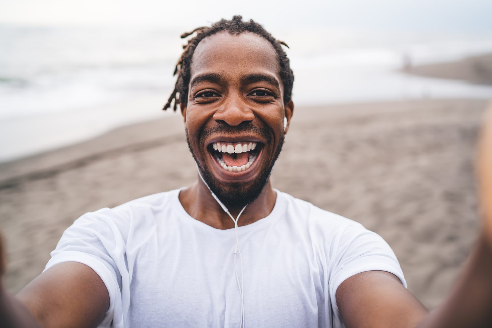 Man laughing joyfully, selfie-style, on a beach