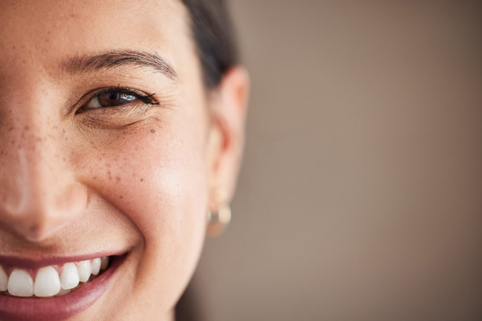 Close-up of a smiling woman's freckled face and eye